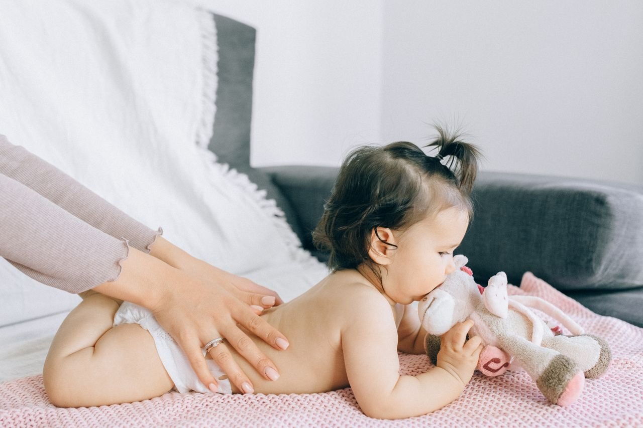 our-story A serene moment of a baby receiving a gentle massage while holding a plush toy, epitomizing peace and comfort.