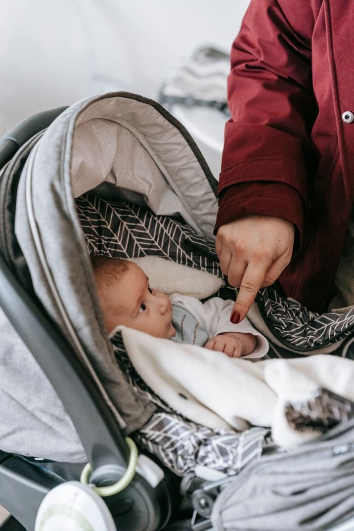 The Art of Drawing Readers In: Your attractive post title goes here Cute newborn comfortably lying in stroller, interacting with caretaker's hand indoors.